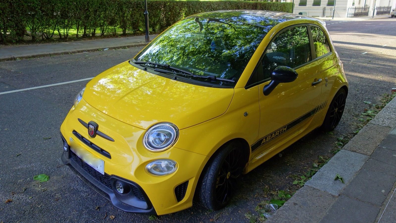 Yellow Abarth 595 with black side stripes, front three-quarter view