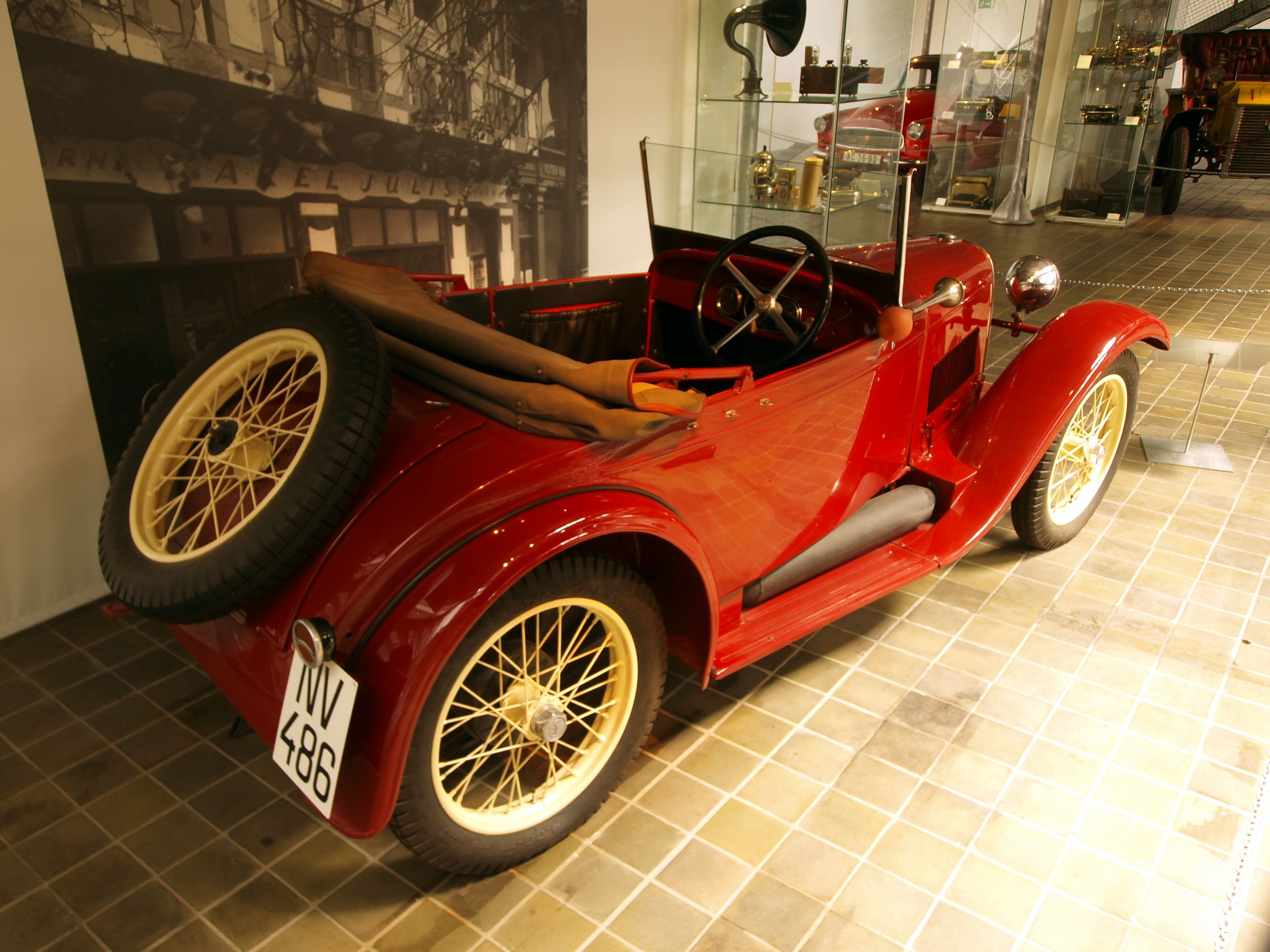 Red 1930 Aero 10 HP roadster on museum display, rear three-quarter view