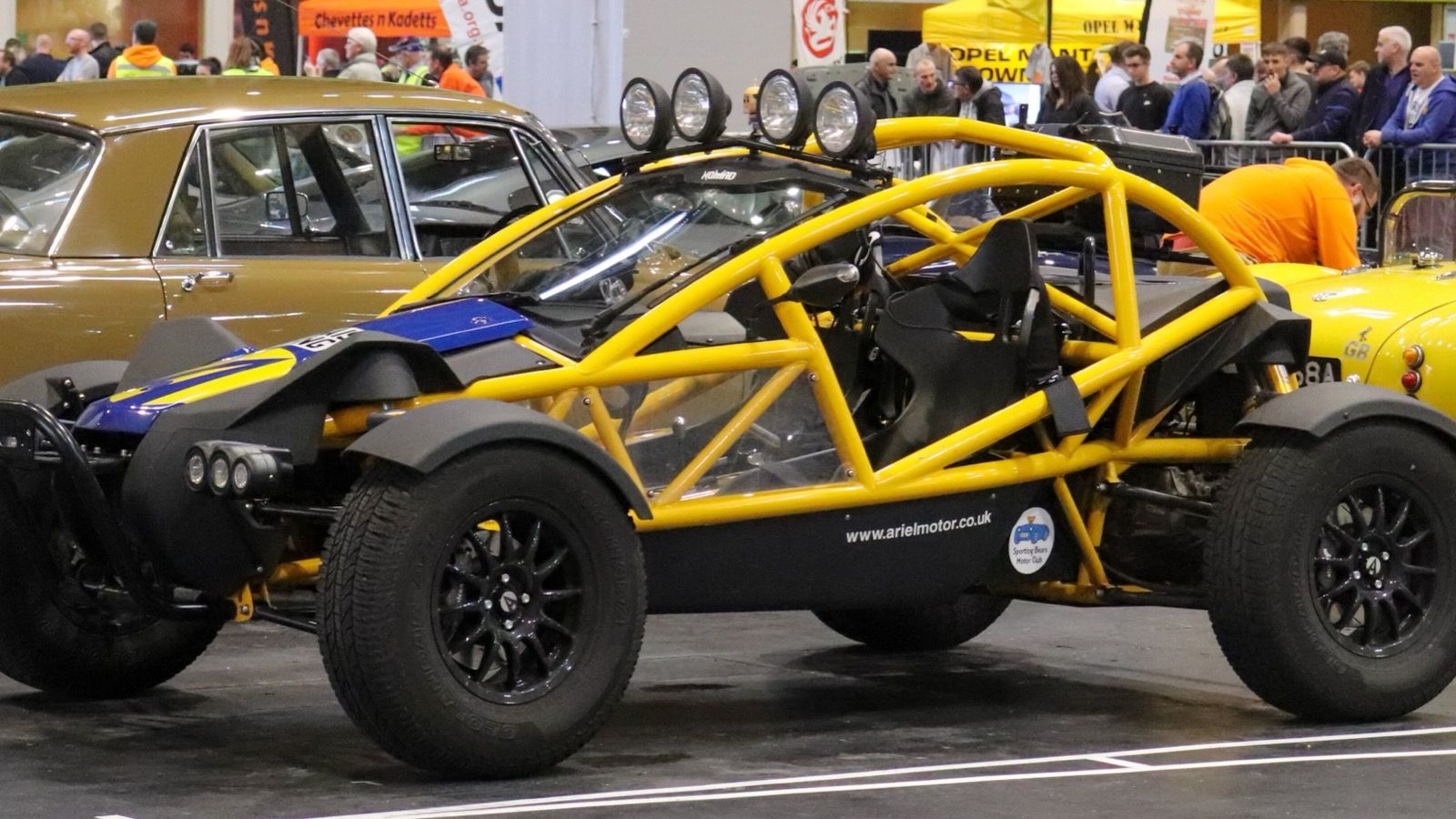 Yellow and blue Ariel Nomad 2.4 with roof light bar, front three-quarter view