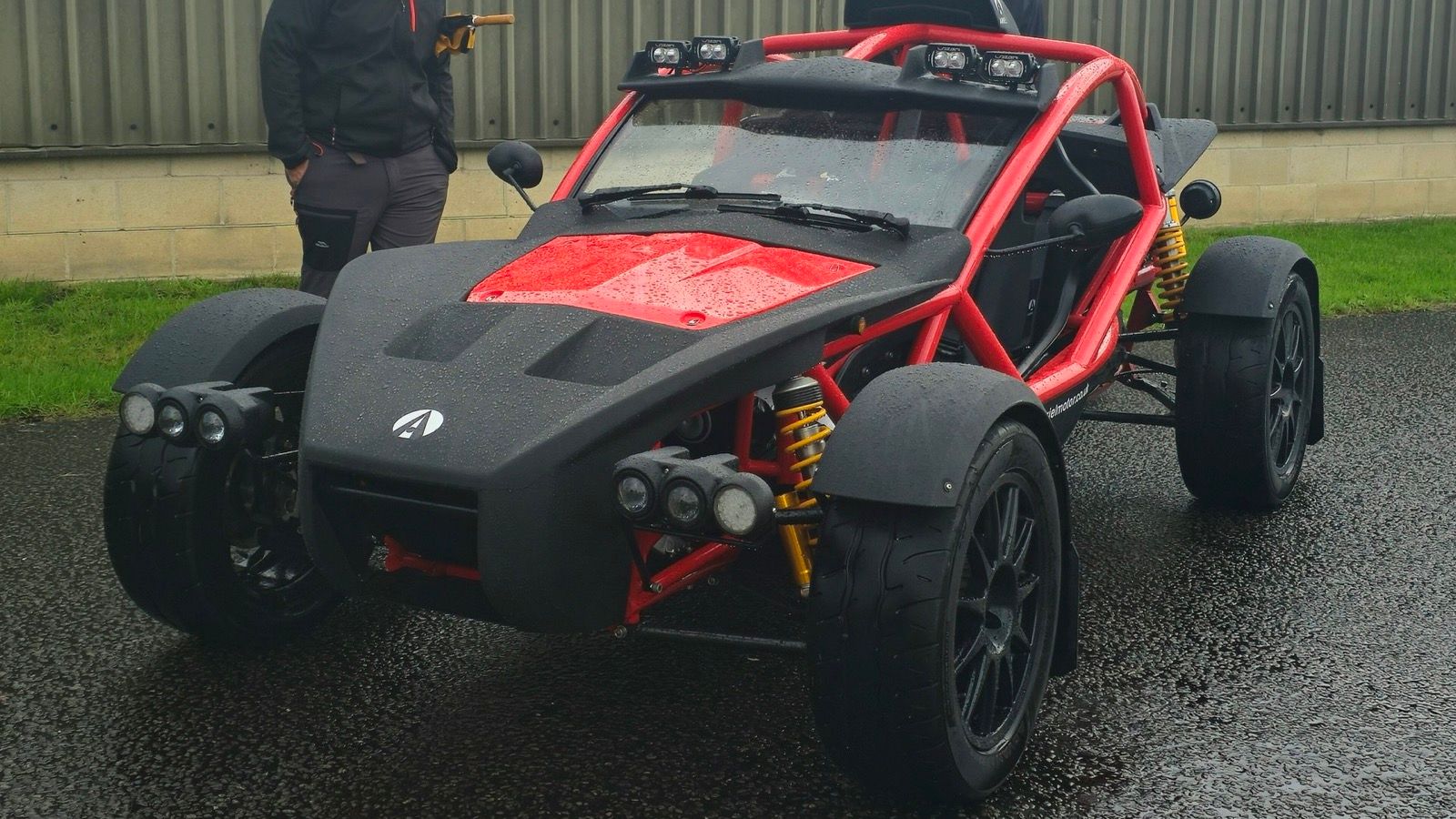 Red and black Ariel Nomad 2 on a wet road, front three-quarter view