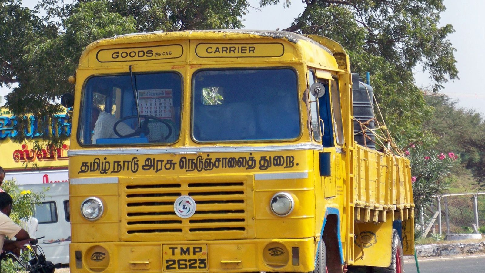 Yellow second-generation Ashok Leyland Comet flatbed truck of the Tamil Nadu State Highways Department, front three-quarter view