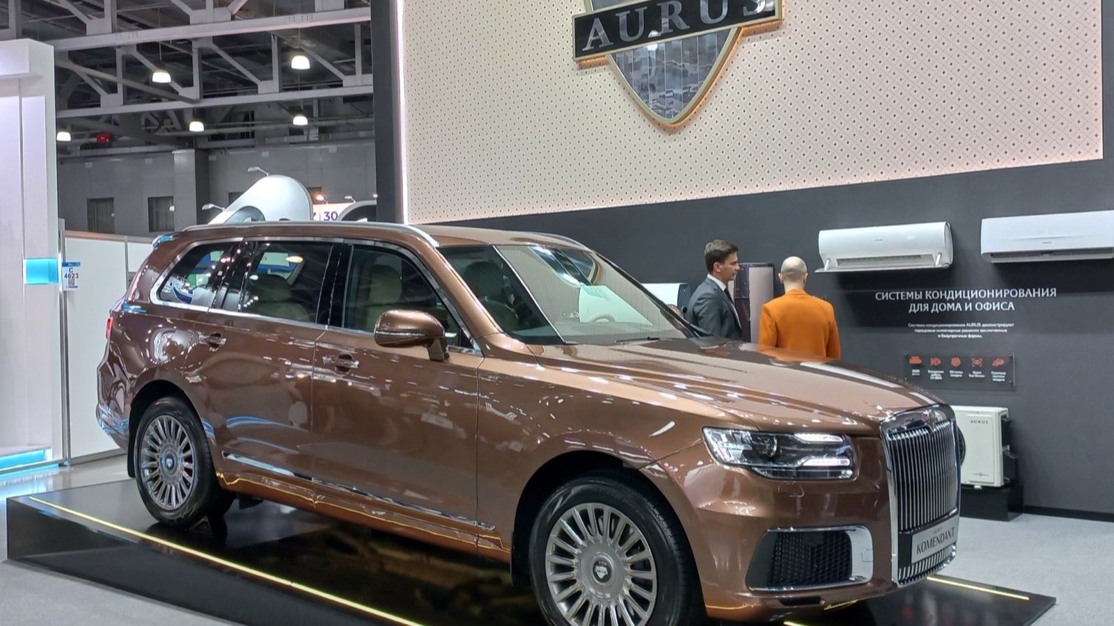 Bronze Aurus Komendant SUV, front three-quarter view, on an Aurus show stand in Moscow