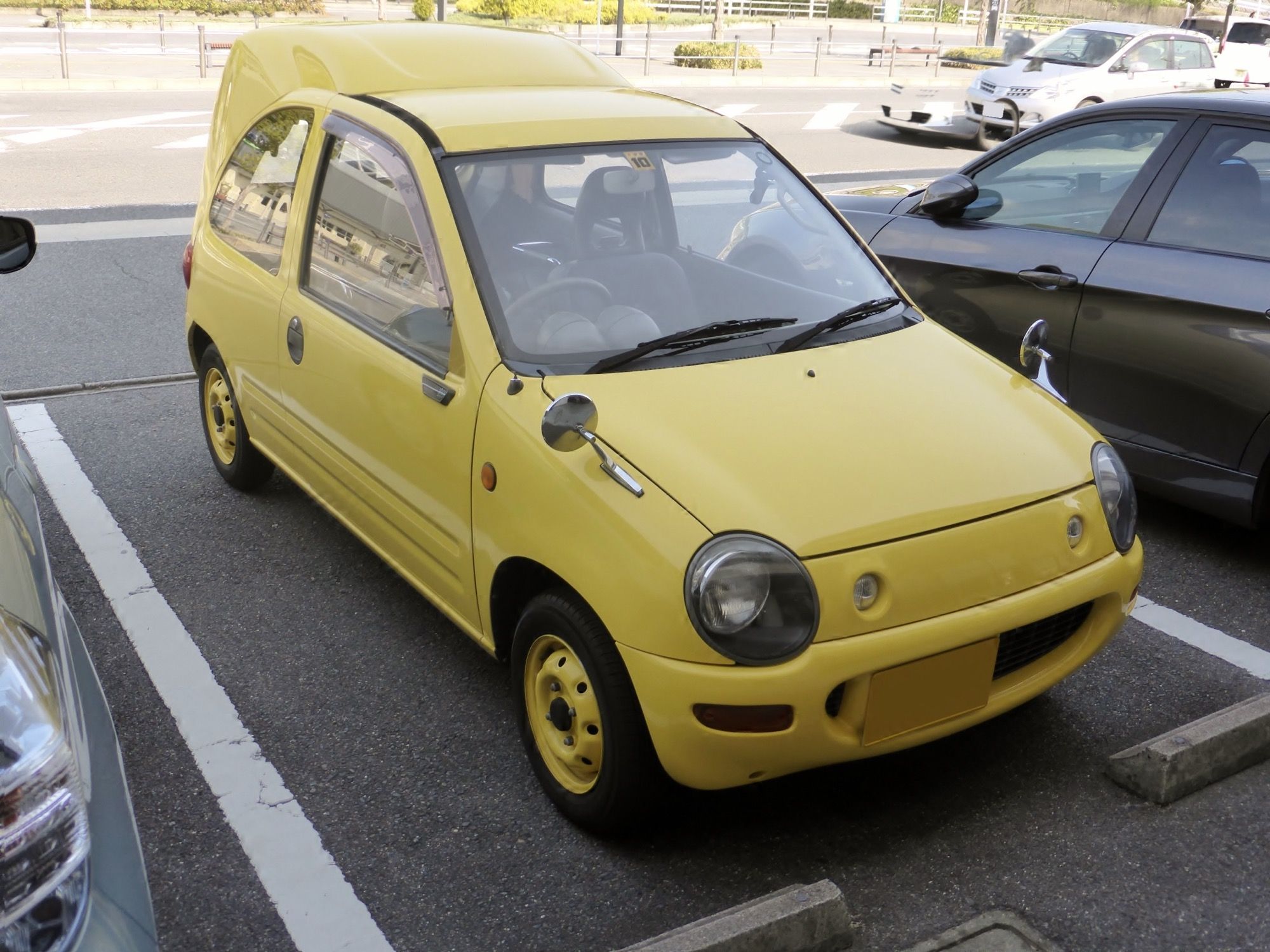 Yellow Autozam Carol AA kei hatchback, front three-quarter view