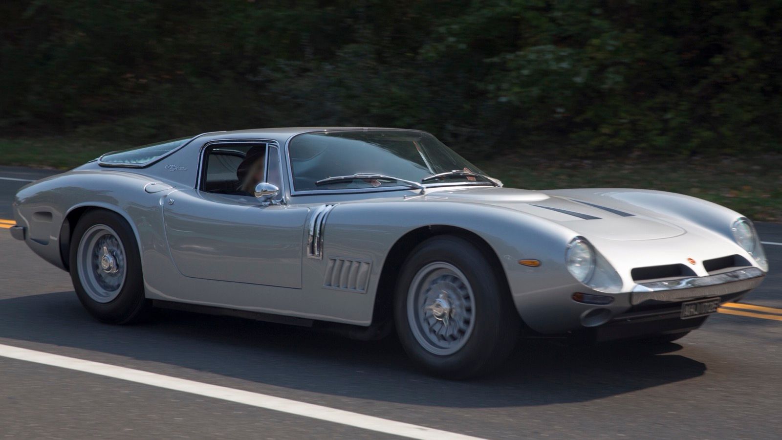 Silver 1967 Bizzarrini 5300 GT Strada driving, front three-quarter view