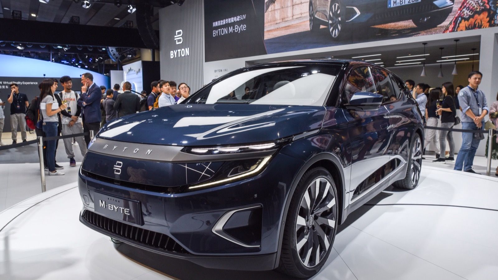 Dark blue Byton M-Byte production-form electric SUV, front three-quarter view on an auto-show stand