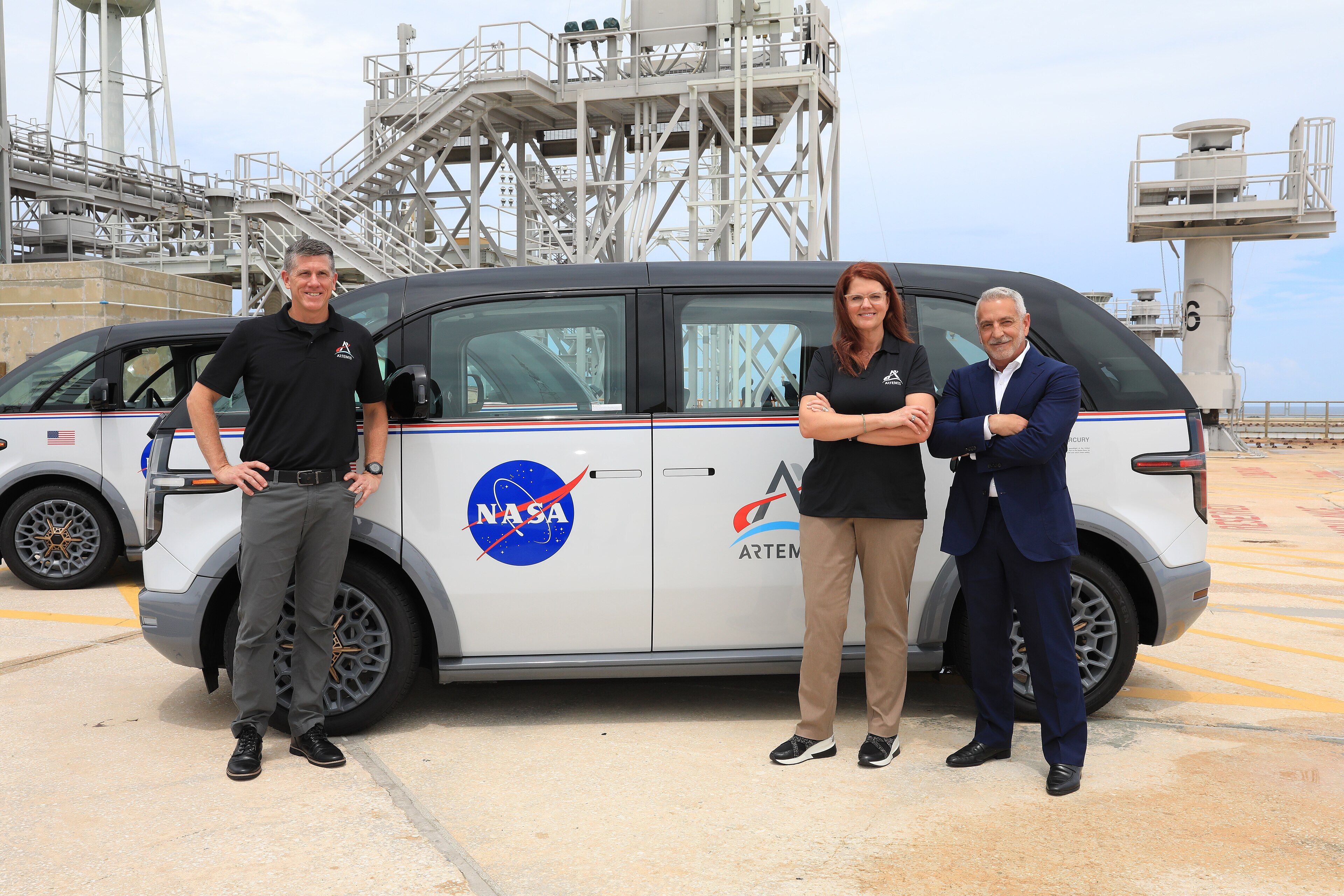 White 2023 Canoo Lifestyle Vehicle in NASA Artemis crew-transport livery, side view at Kennedy Space Center