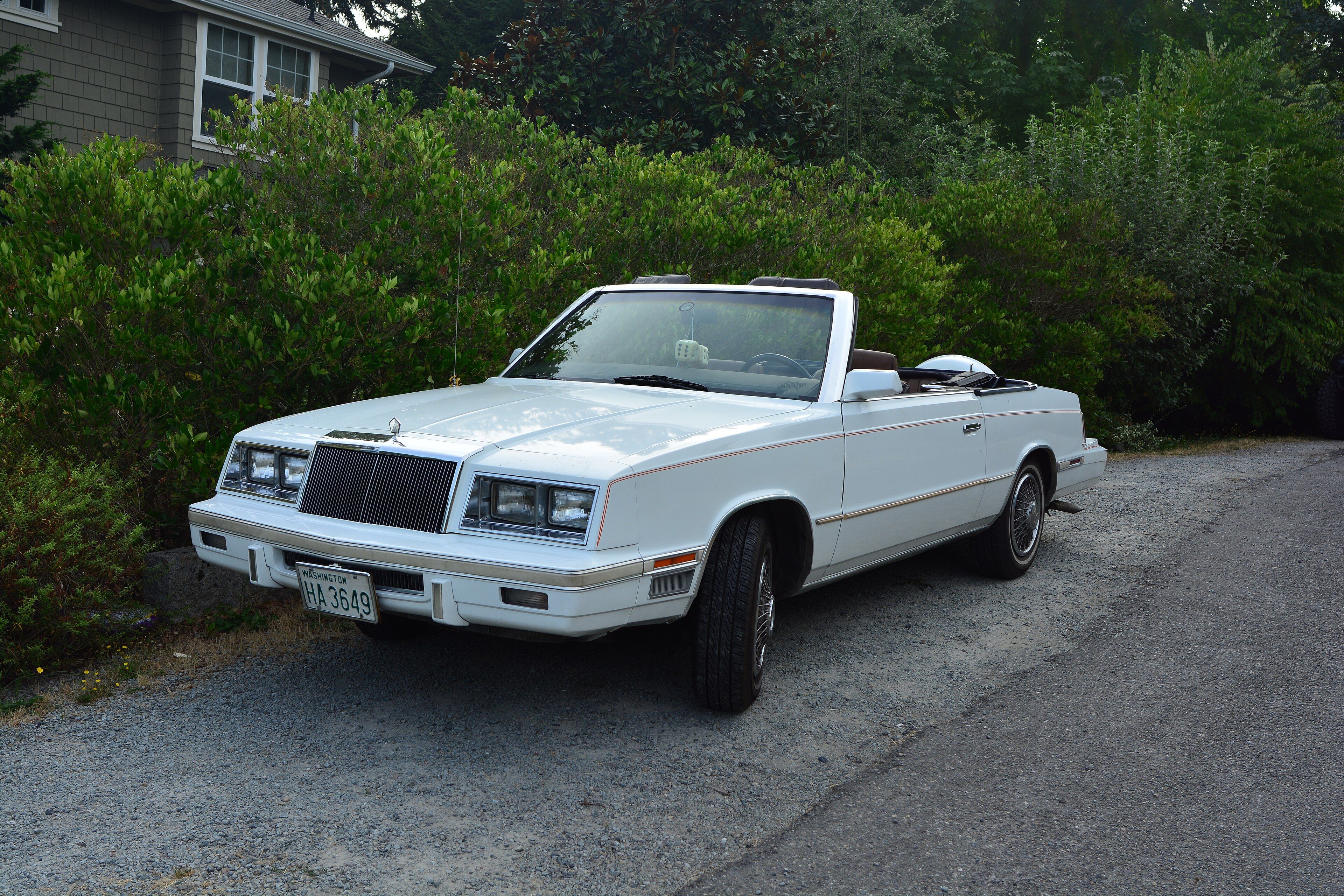 White 1984 Chrysler LeBaron convertible with the top down, front three-quarter view