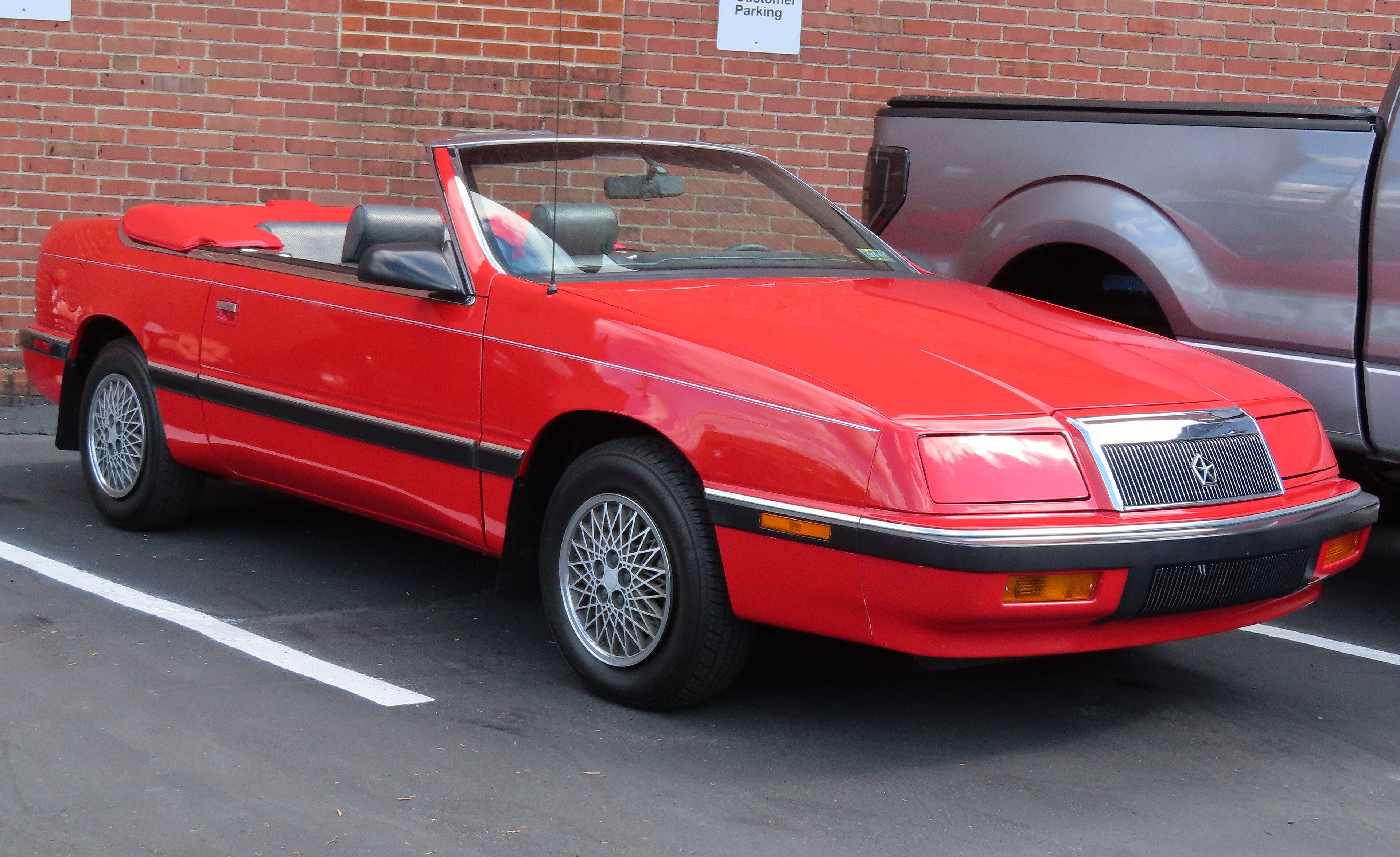 Red 1989 Chrysler LeBaron convertible with the top down, front three-quarter view