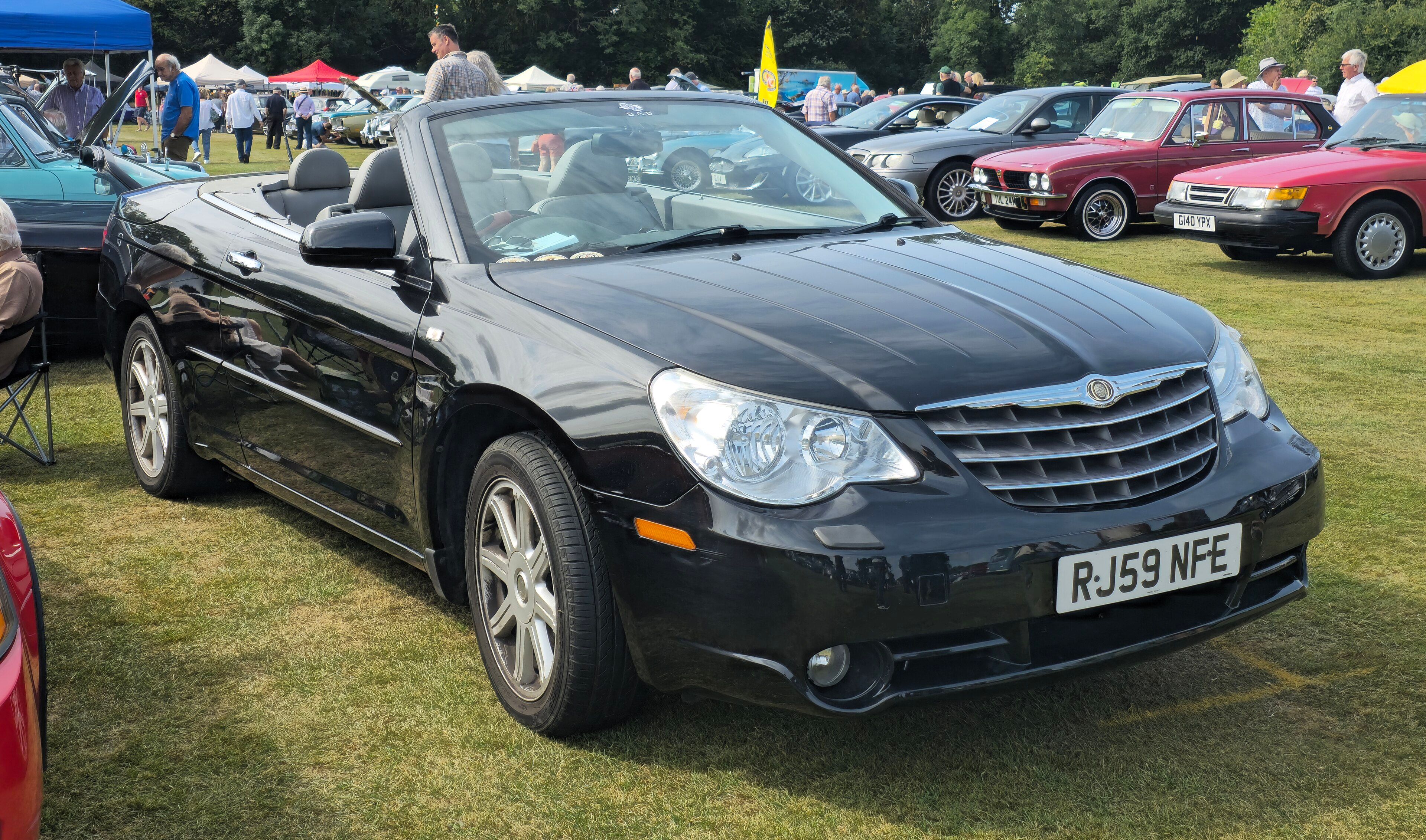 Black 2009 Chrysler Sebring Limited convertible with the top down at a car show, front three-quarter view