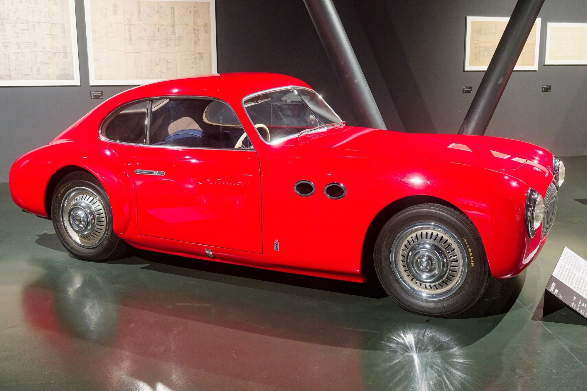 Red Cisitalia 202 coupe, side profile in a museum