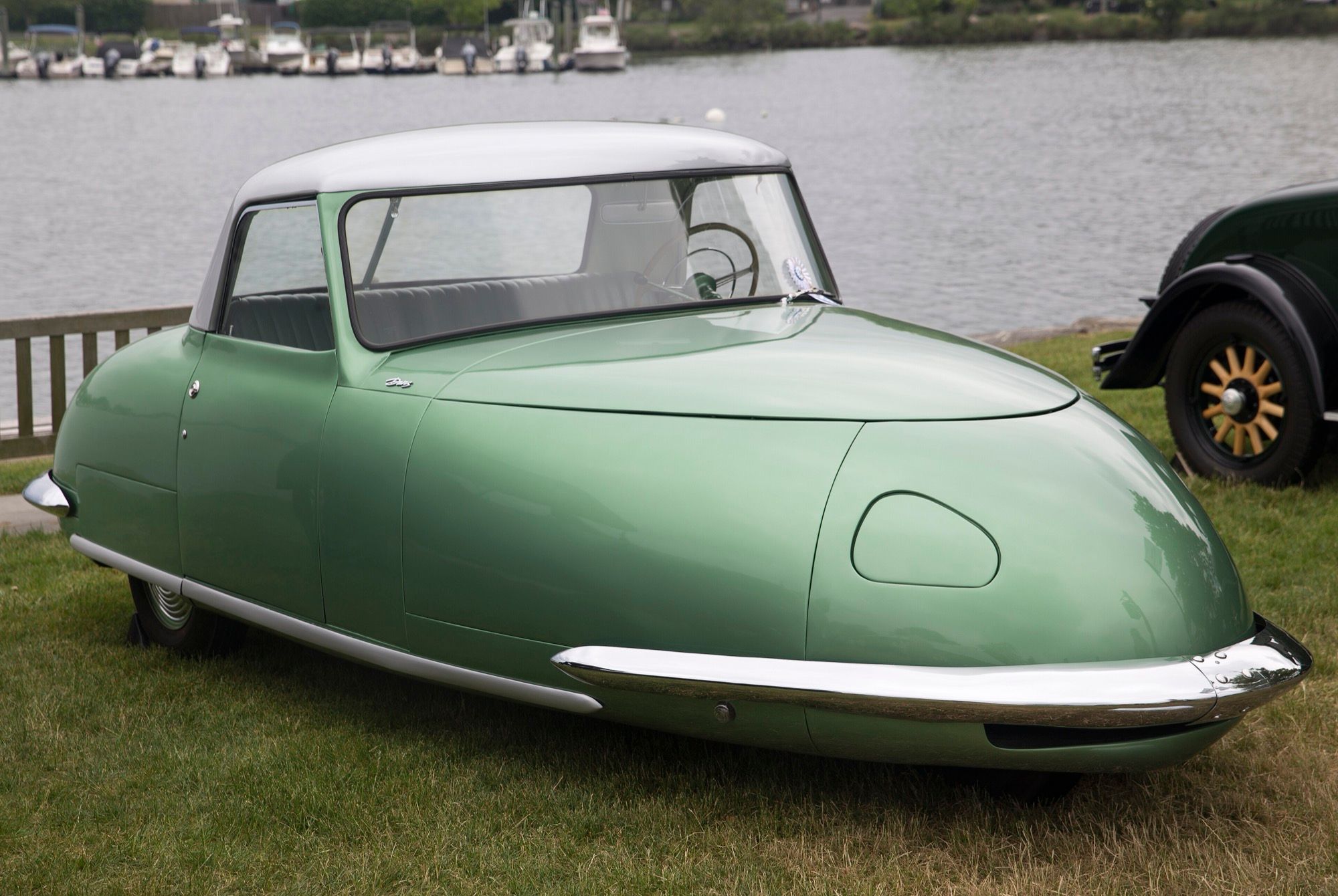Green 1948 Davis Divan three-wheeled convertible with white hardtop, front three-quarter view, parked by a harbor