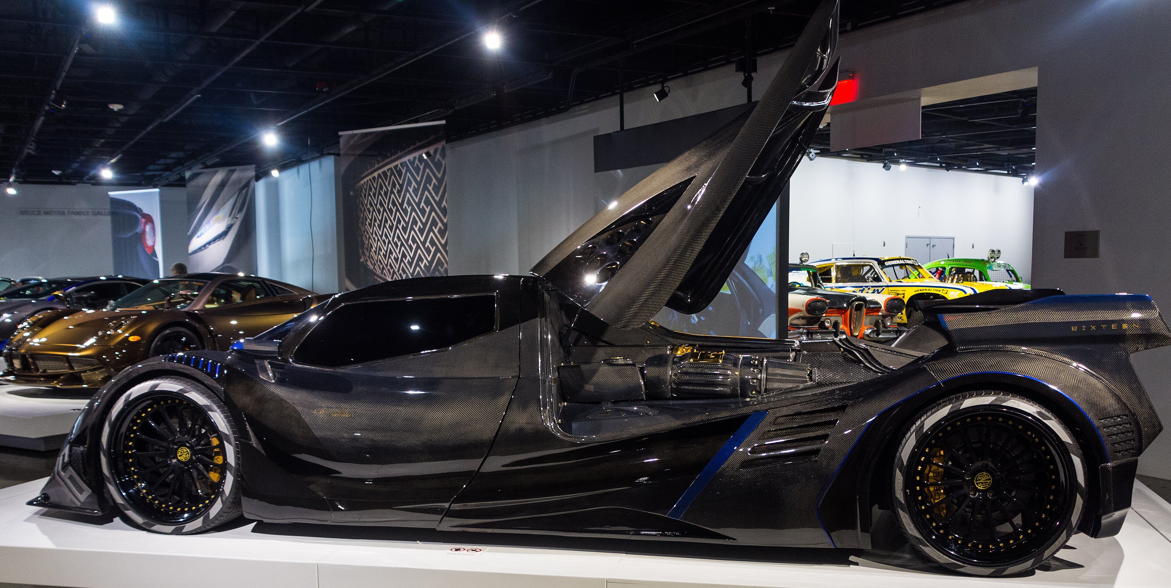 Black carbon-fibre 2020 Devel Sixteen V-8 prototype with door raised, side profile view