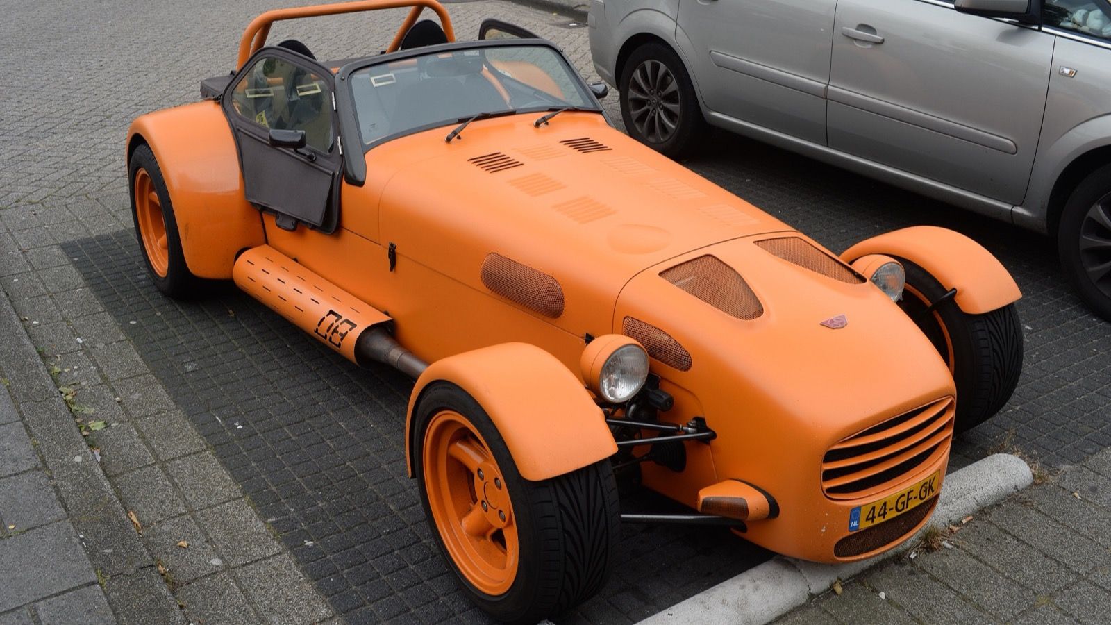 Orange 2000 Donkervoort D8-150 roadster parked kerbside, front three-quarter view