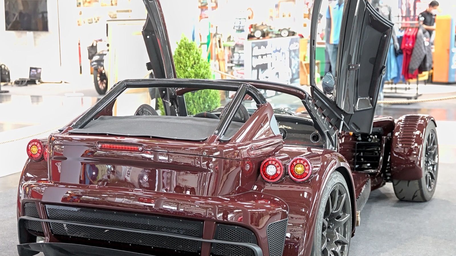 Dark red Donkervoort D8 GTO-JD70 with butterfly doors open on the IAA 2021 show stand, rear three-quarter view