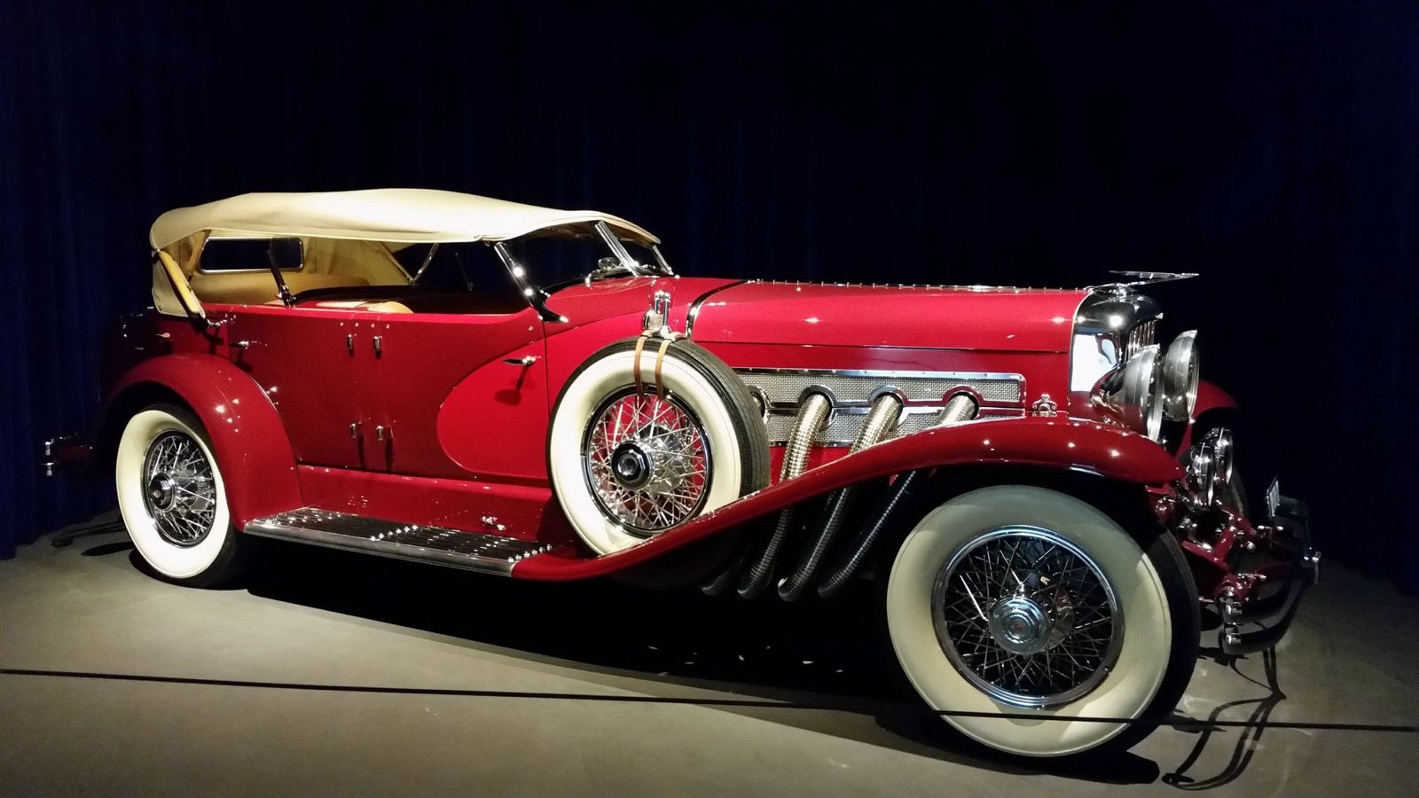 Red 1935 Duesenberg Model SJ LaGrande dual-cowl phaeton, side profile view