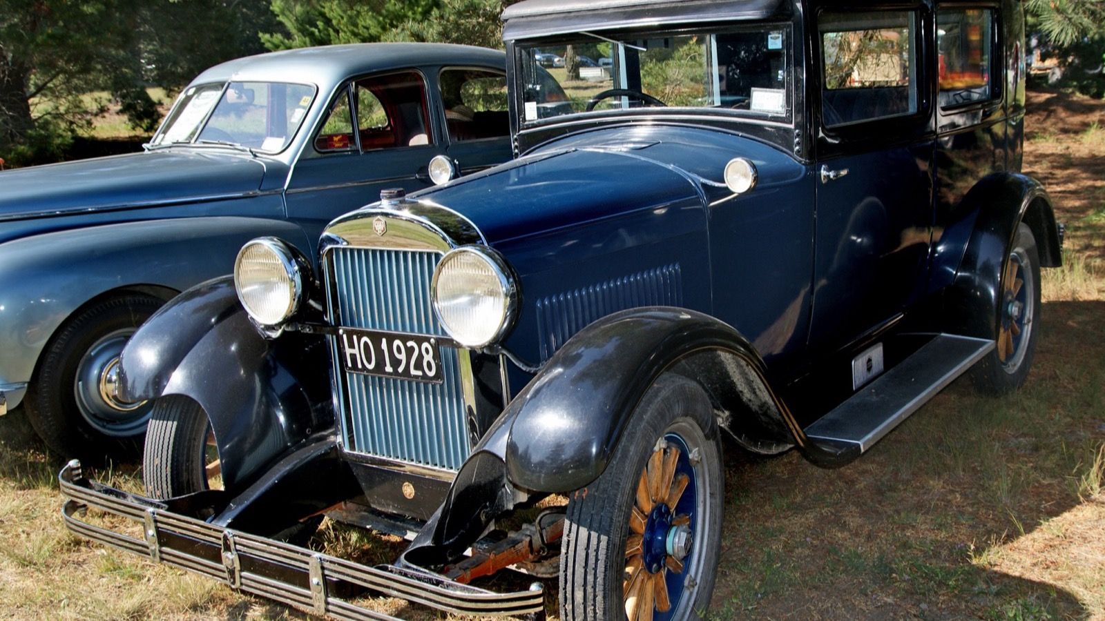 Dark blue 1928 Essex Super Six sedan parked under trees, front three-quarter view