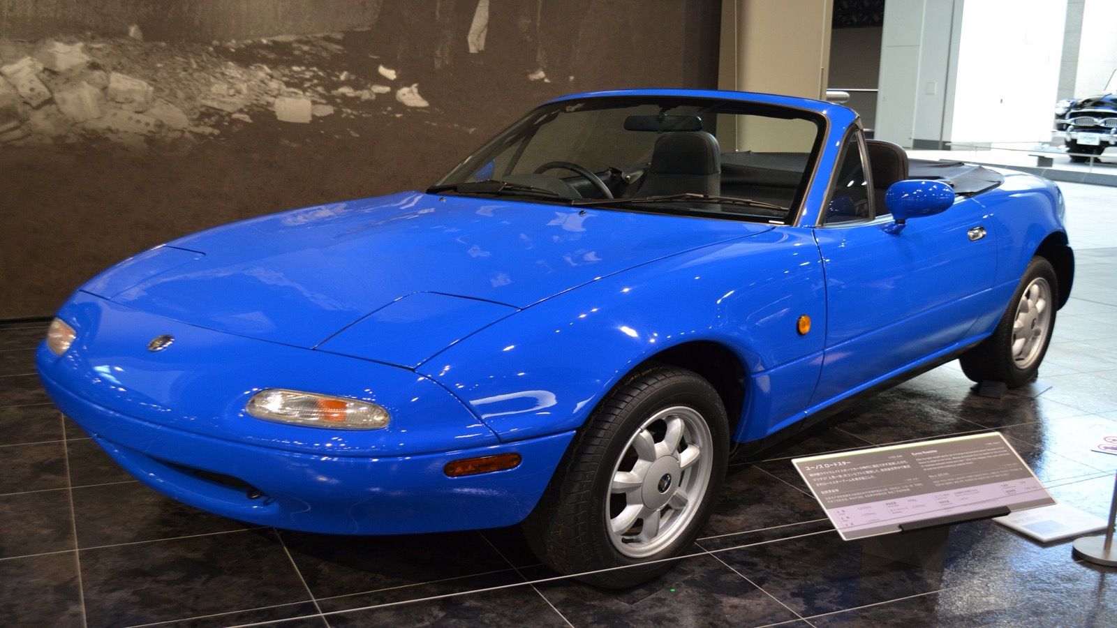 Eunos Roadster (NA) in blue with the roof down, front three-quarter view