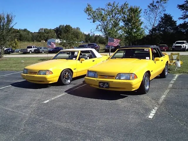 Two Canary Yellow 1993 Ford Mustang LX 5.0 Feature Edition convertibles with chrome Pony wheels