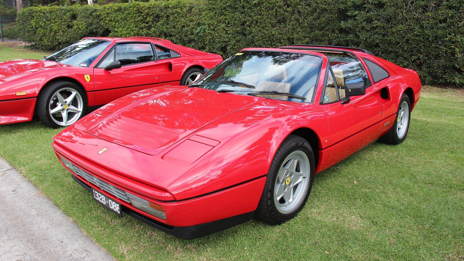 Red 1987 Ferrari 328 GTS targa on grass, front three-quarter view