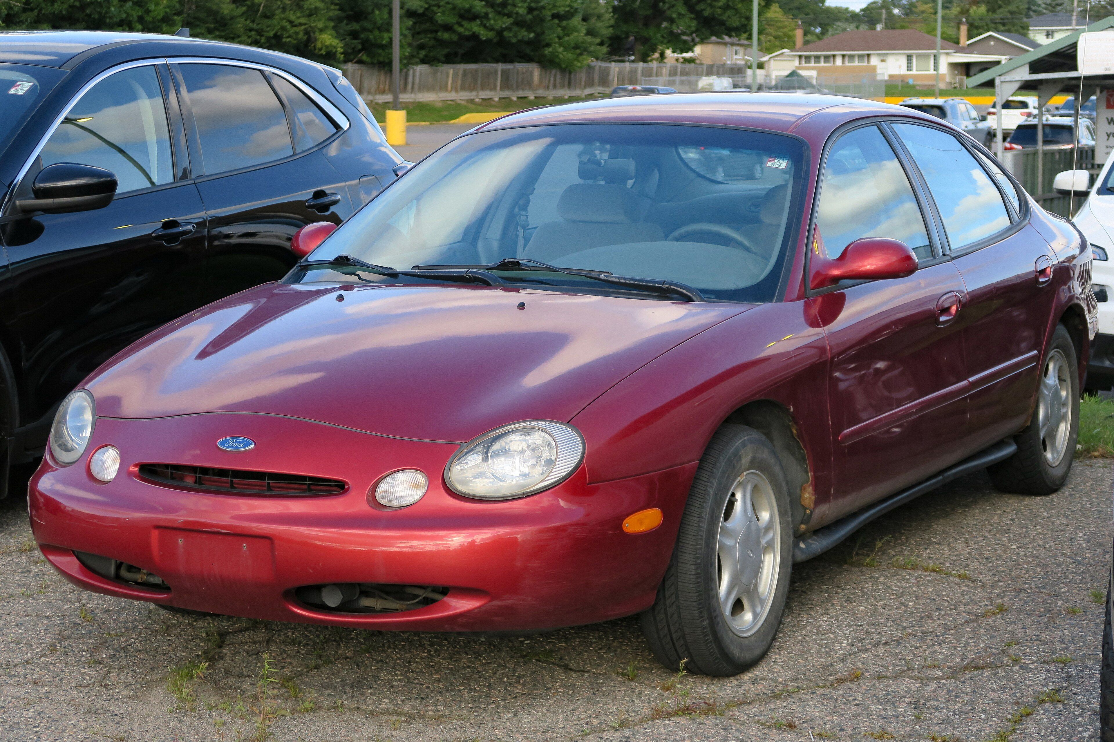 Red 1997 Ford Taurus GL sedan, front three-quarter view showing the oval styling theme