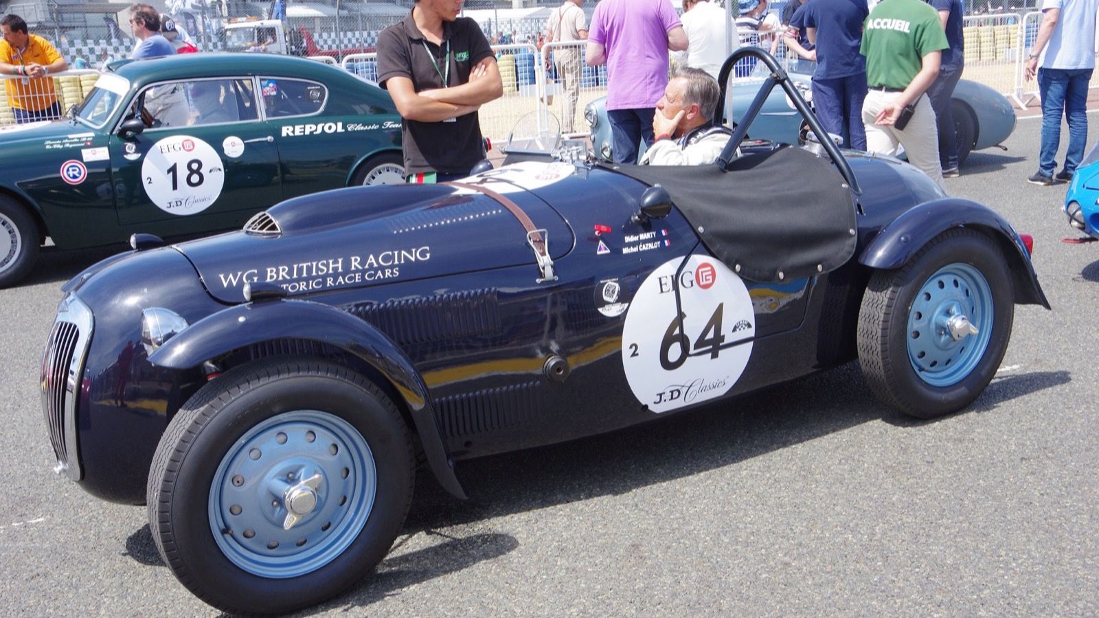 Dark blue 1950 Frazer Nash Le Mans Replica open roadster in a race paddock, left side view