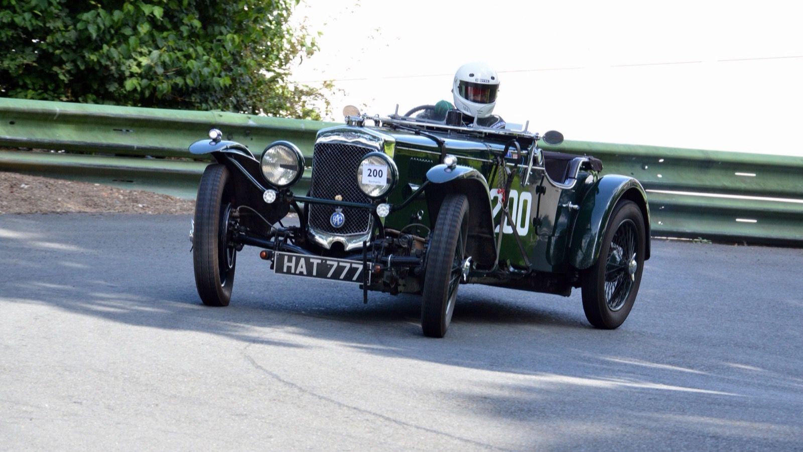 Green 1933 Frazer Nash TT Replica open two-seater on track, front three-quarter view