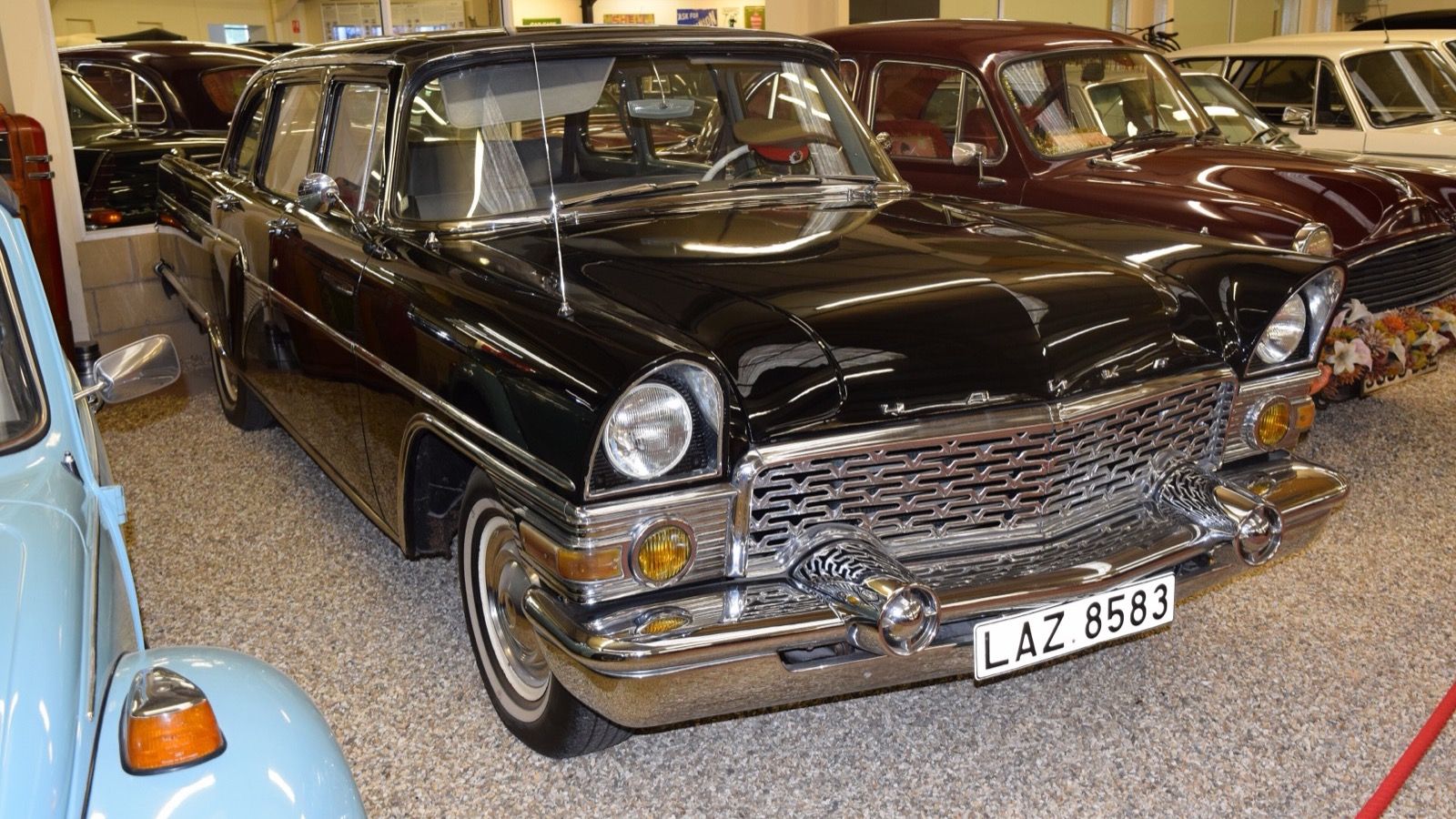 Black 1959 GAZ-M13 Chaika saloon in a museum hall, front three-quarter view