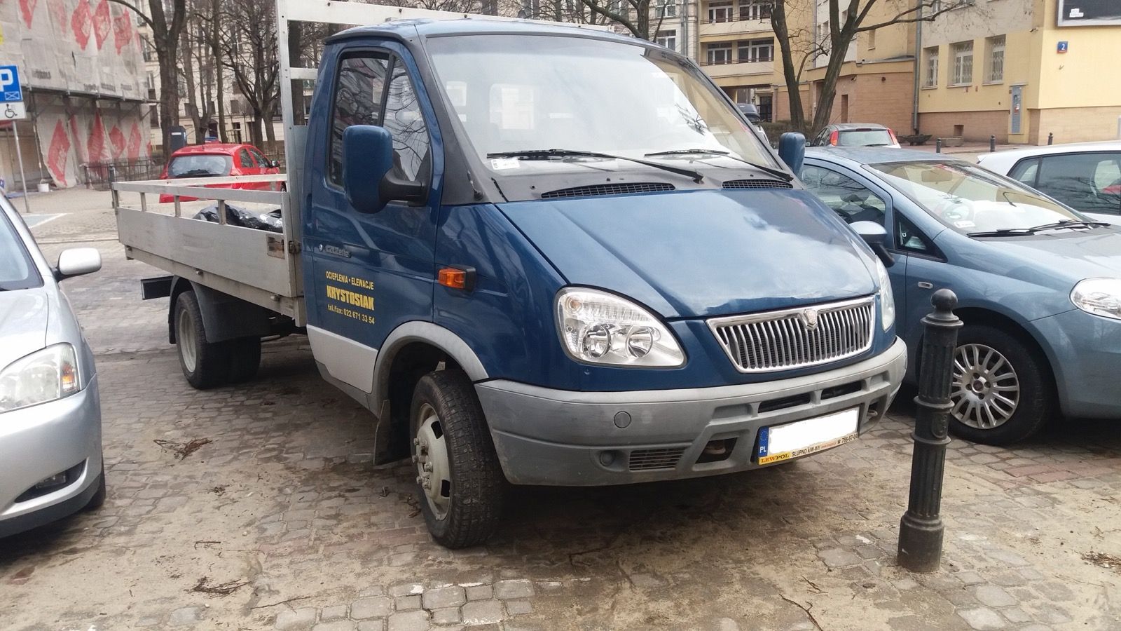 Blue GAZ-3302 GAZelle flatbed truck parked on a cobbled street in Warsaw, front three-quarter view