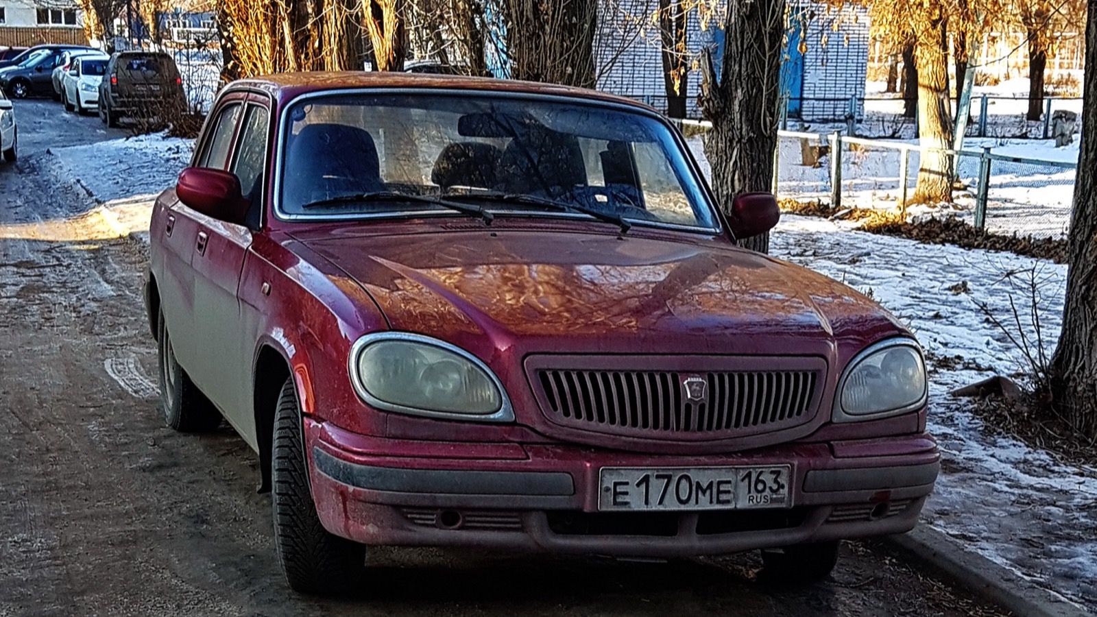 Dark red 2004 GAZ-31105 Volga saloon parked on a snowy street, front three-quarter view