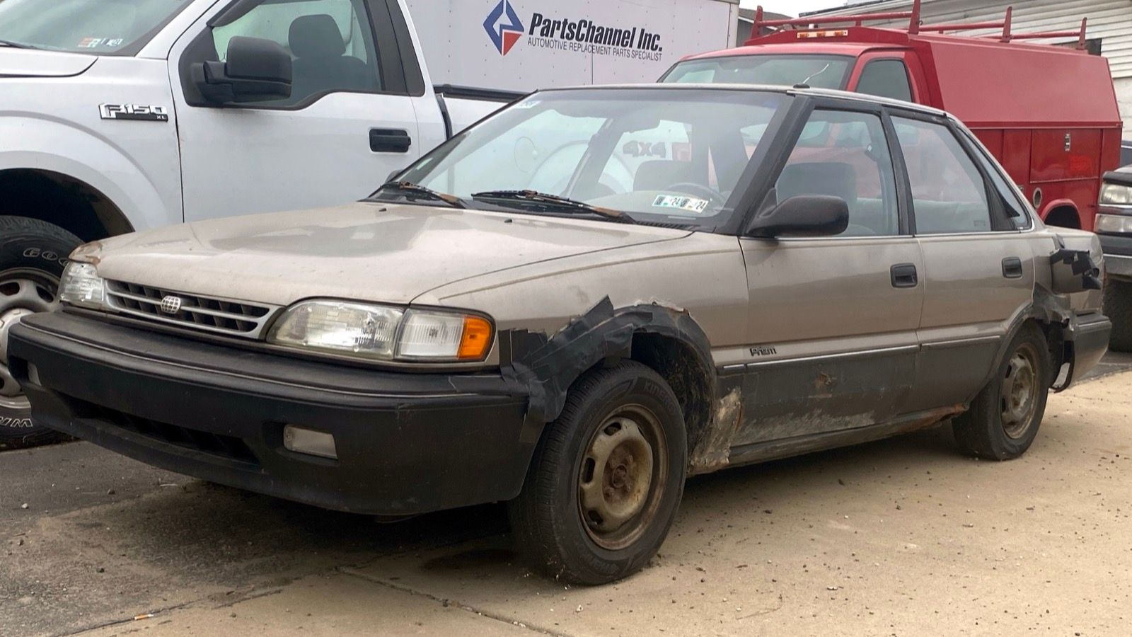 Dark brown 1990 Geo Prizm sedan, front three-quarter view