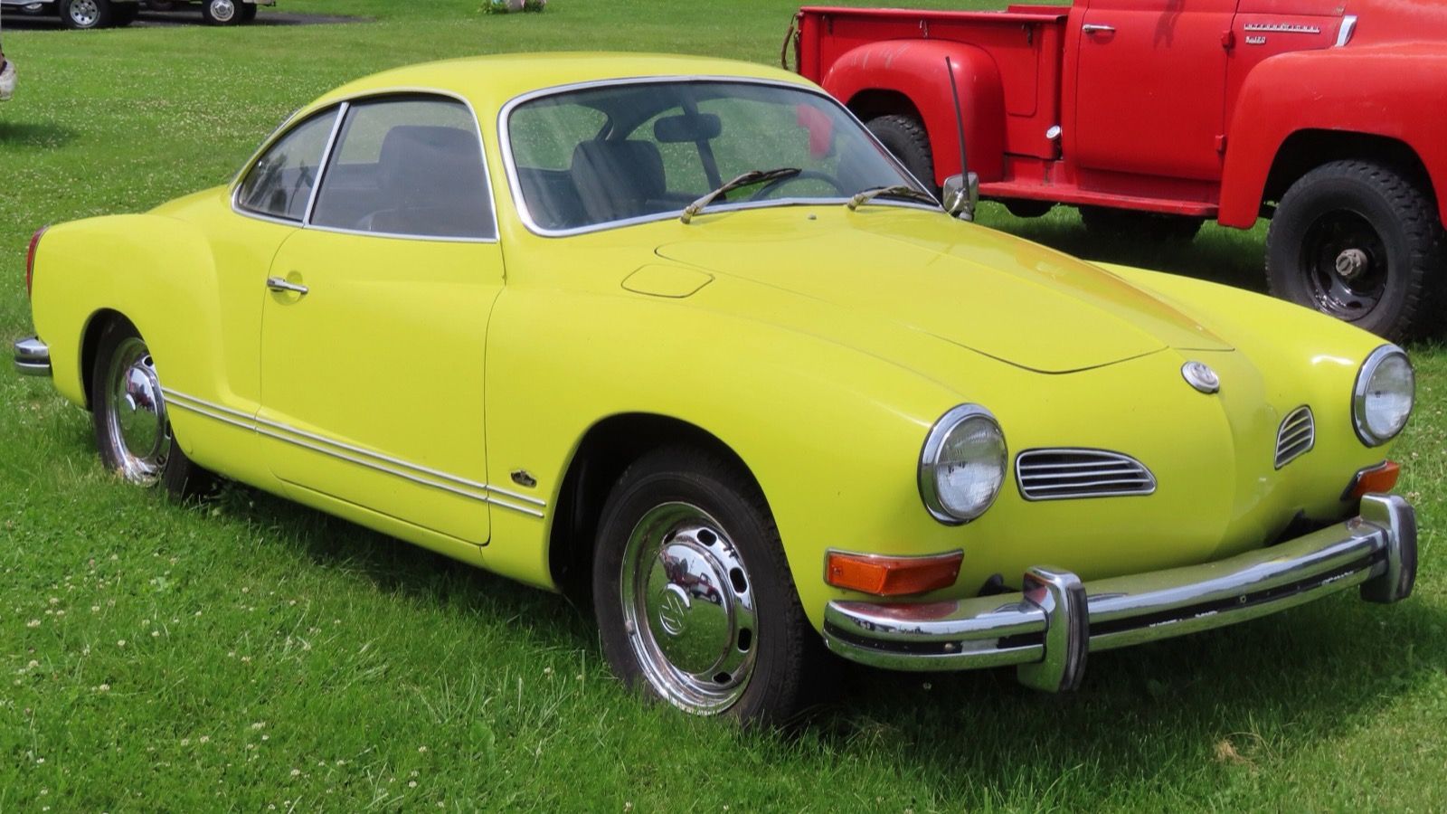 Yellow 1972 Volkswagen Karmann Ghia coupé with raised-height bumpers, front three-quarter view.