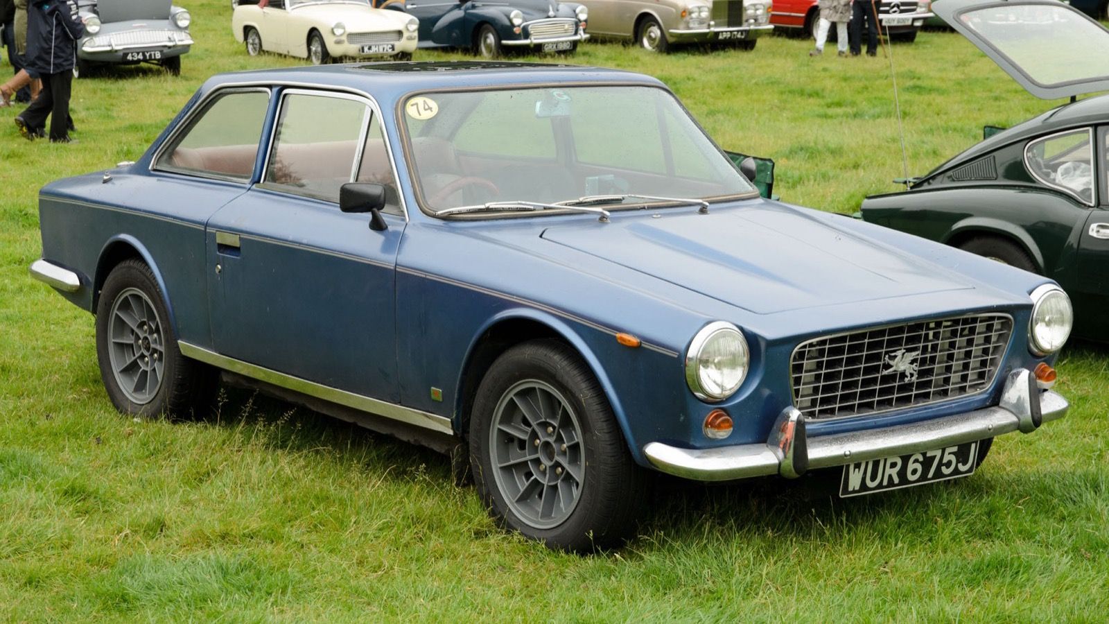 Blue Gilbern Invader coupé, front three-quarter view, showing the chrome mesh grille and Welsh dragon badge.