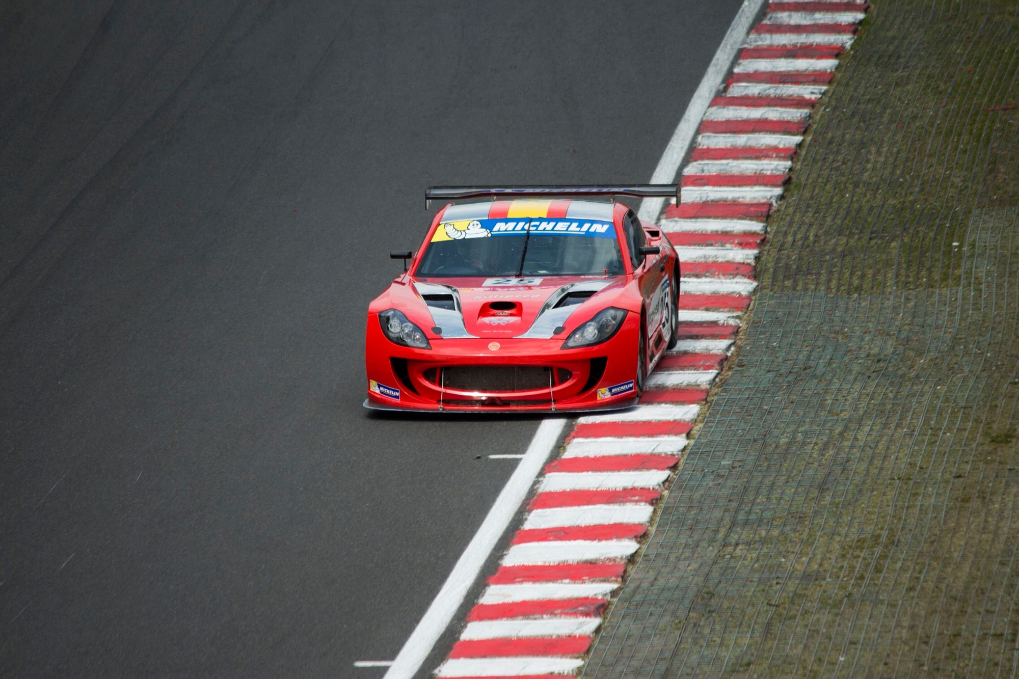Red Ginetta G55 GT Supercup racer at speed at Oulton Park, 2013, front three-quarter view