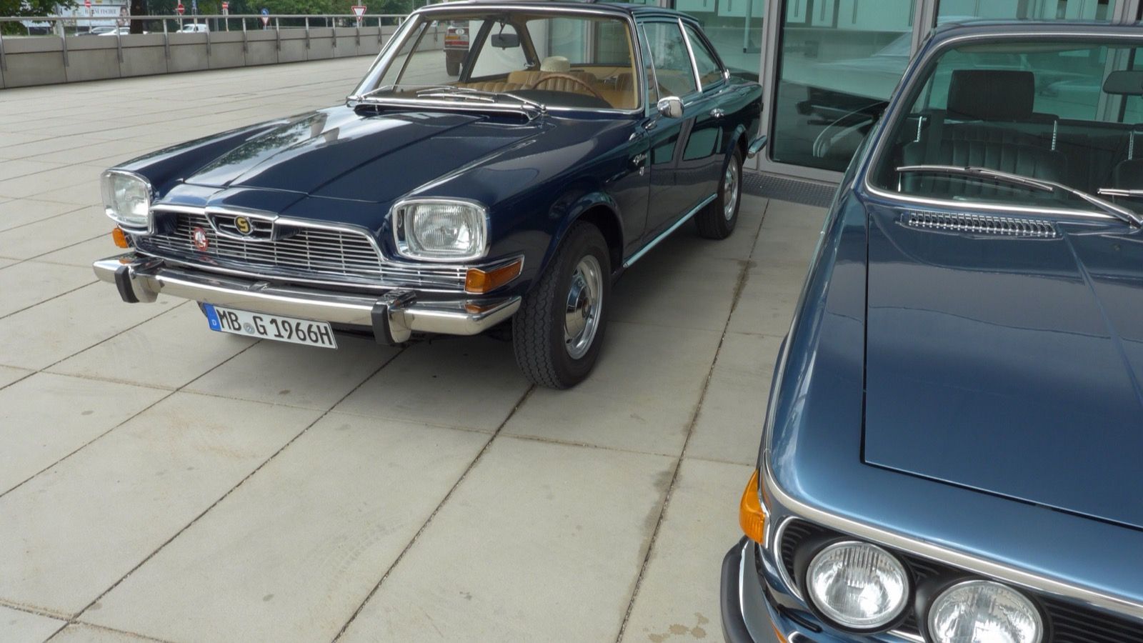 Dark blue 1966 Glas V8 coupé parked on a paved forecourt, front three-quarter view