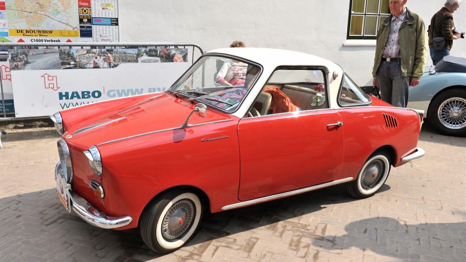 Red 1961 Goggomobil TS 250 coupé with a white roof parked on a cobbled street, front three-quarter view