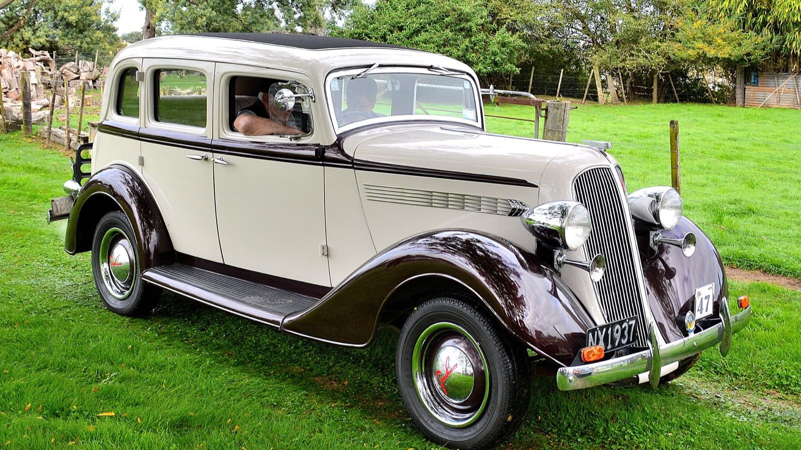 Cream and maroon 1935 Graham sedan parked on grass, front three-quarter view