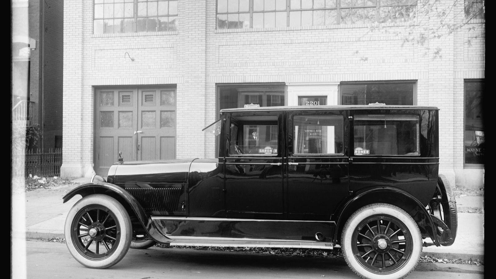 Black 1920 Haynes sedan photographed in side profile at the kerb outside a dealership.