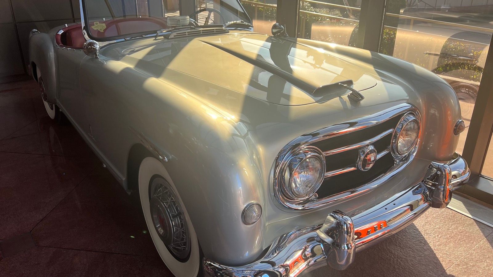 Pale grey 1953 Nash-Healey Pininfarina roadster on museum display, front three-quarter view