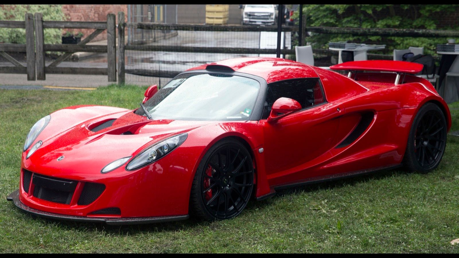 Red 2011 Hennessey Venom GT coupe parked on grass, front three-quarter view
