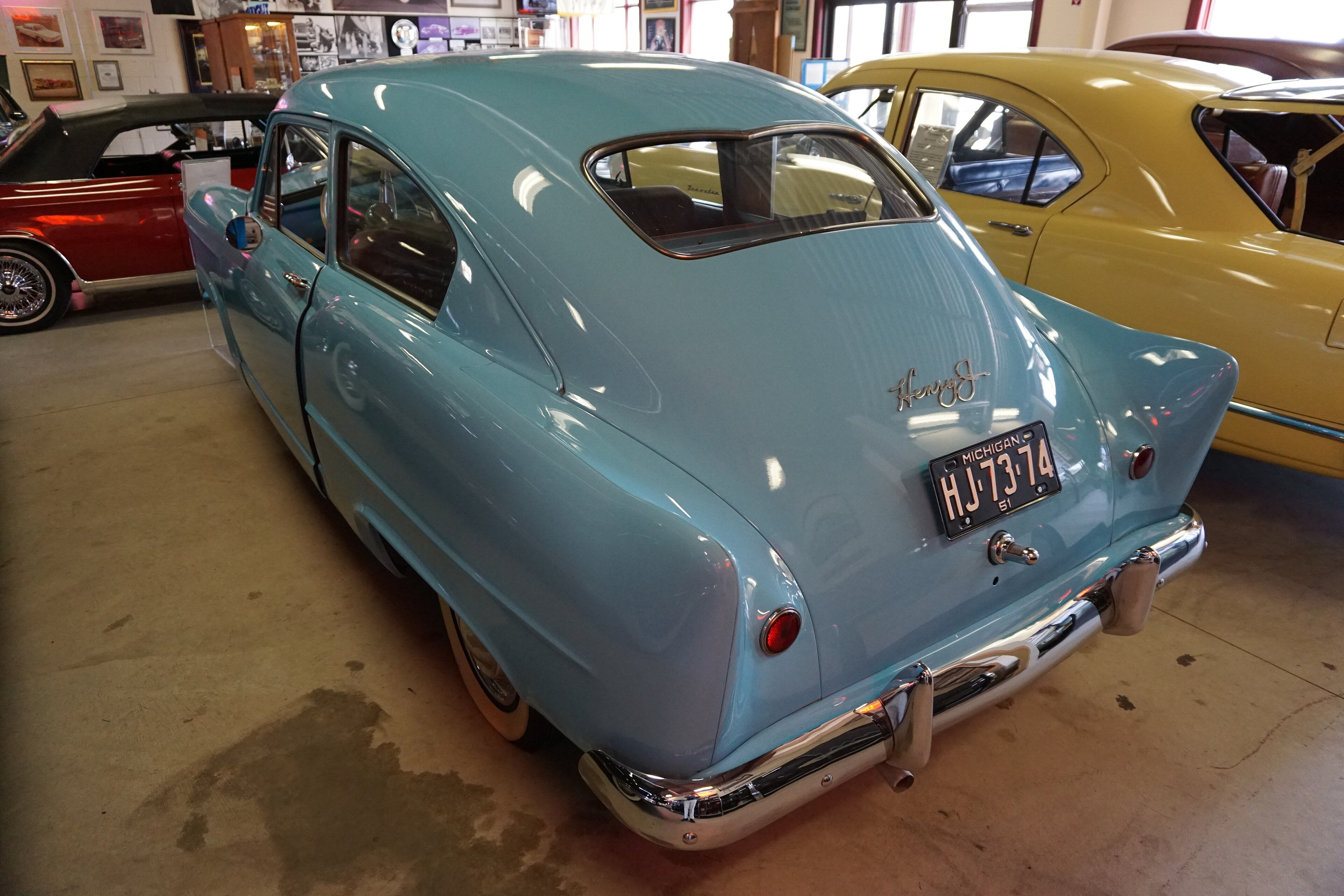 Light blue 1951 Henry J two-door sedan showing the trunk-lid-less rear bodywork, rear three-quarter view