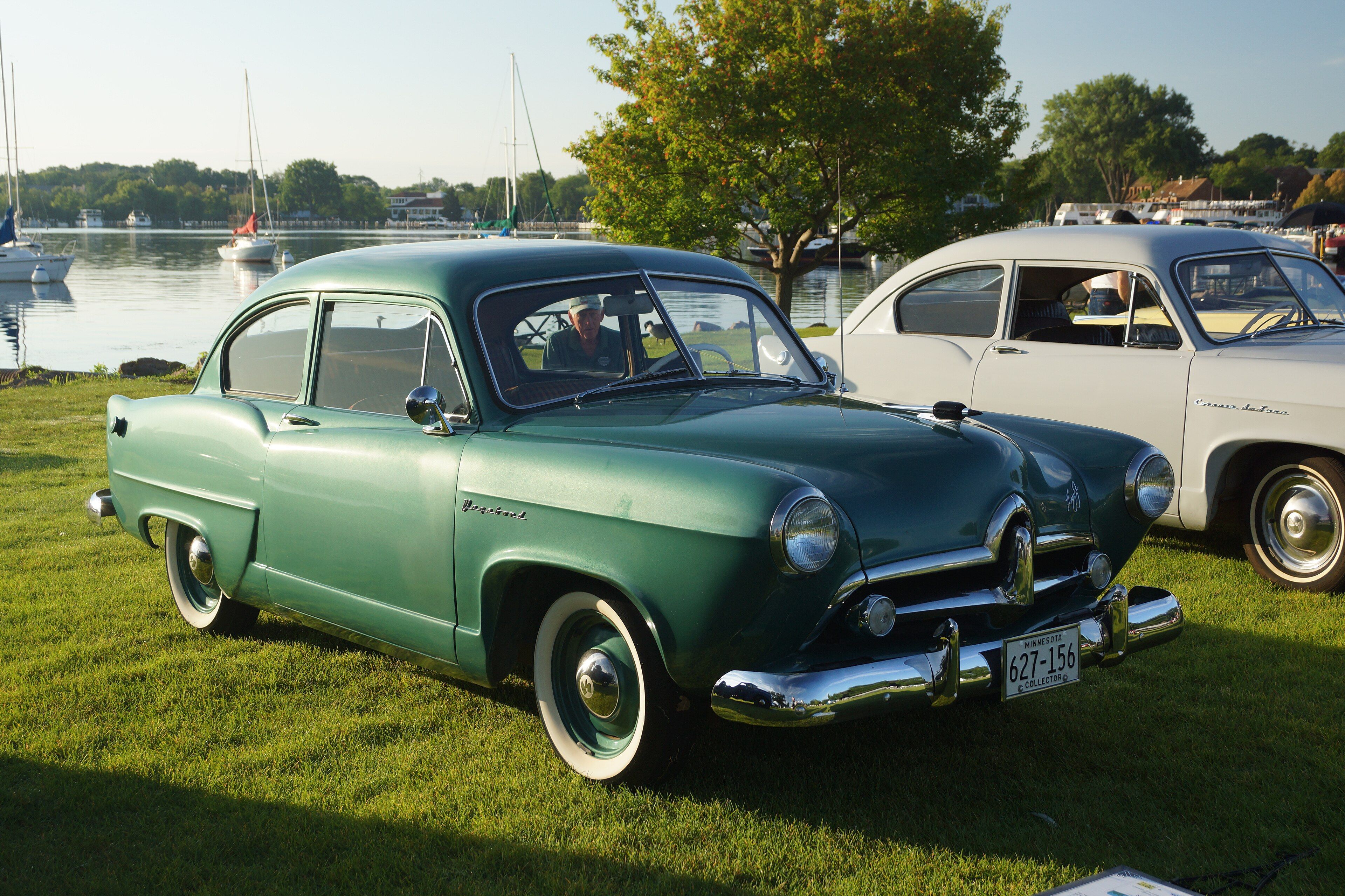 Green 1952 Henry J Vagabond two-door sedan at a lakeside car show, front three-quarter view