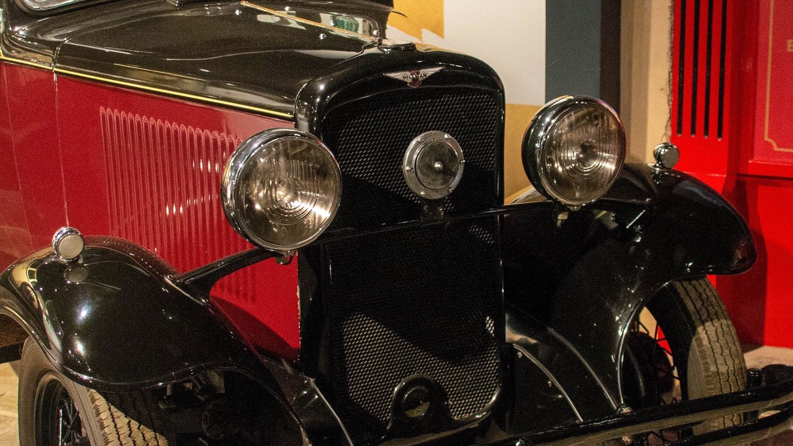 Red and black 1932 Hillman Minx six-light saloon on museum display, front three-quarter view