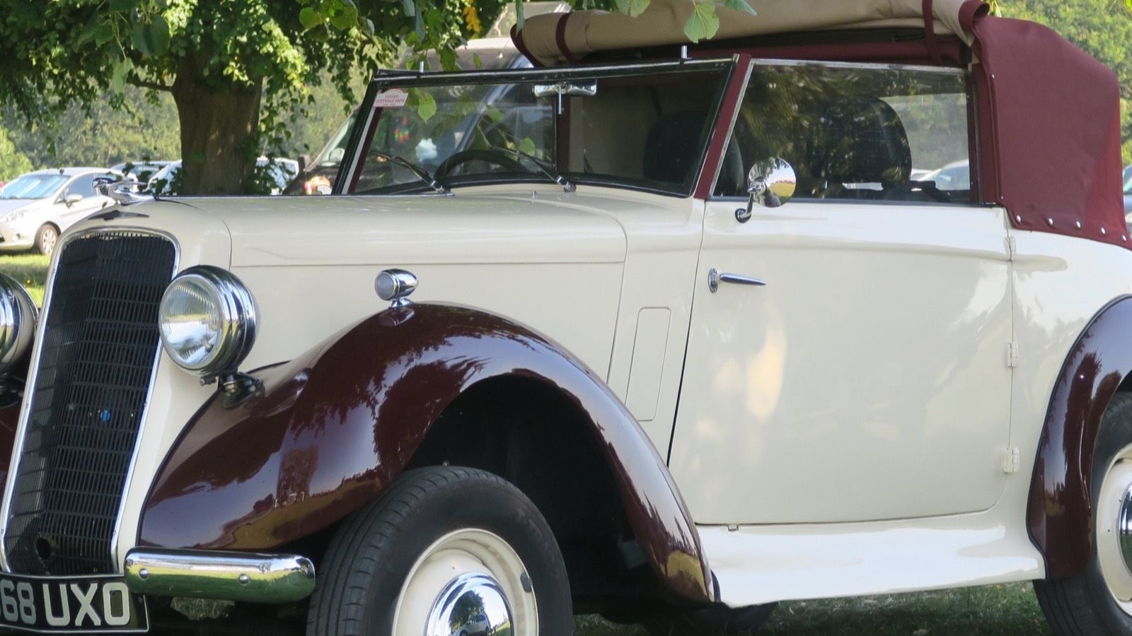 Cream and maroon 1935 Hillman Minx Magnificent drophead coupé parked under a tree, front three-quarter view