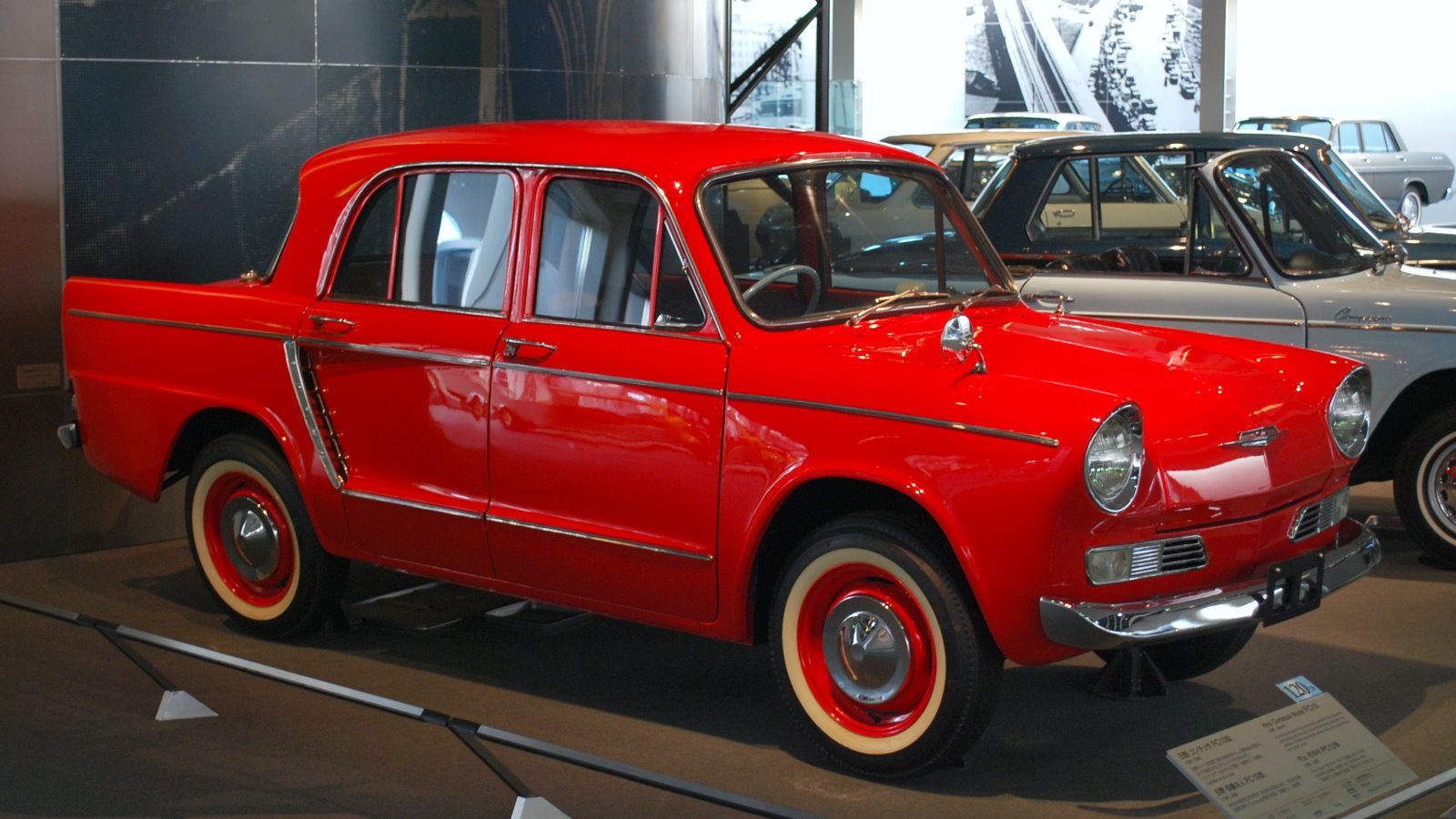 Red 1961 Hino Contessa 900 (PC10) four-door sedan on museum display, front three-quarter view