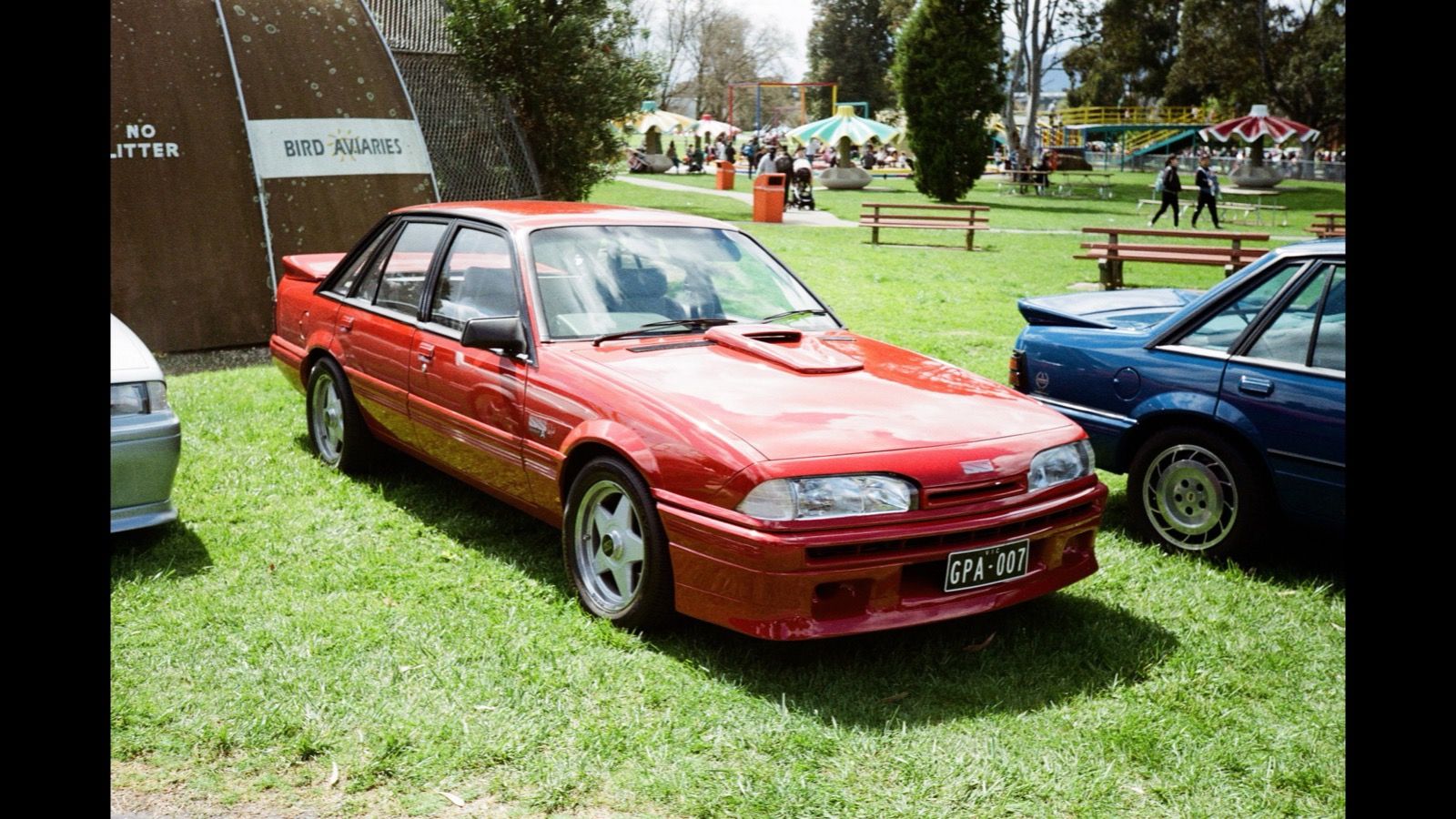 Red 1986 Holden Commodore SS Group A sedan on grass, front three-quarter view