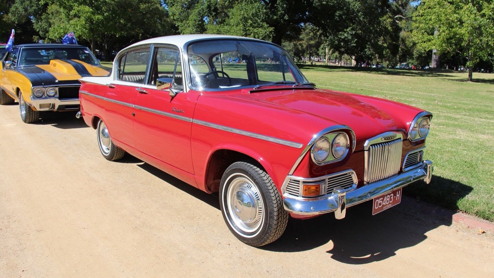 Red and white 1963 Humber Sceptre Mk I saloon in a park, front three-quarter view
