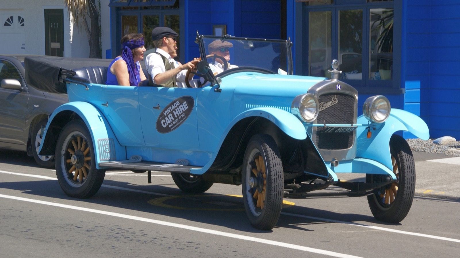 Light blue 1925 Hupmobile Model R open tourer being driven on a street, front three-quarter view
