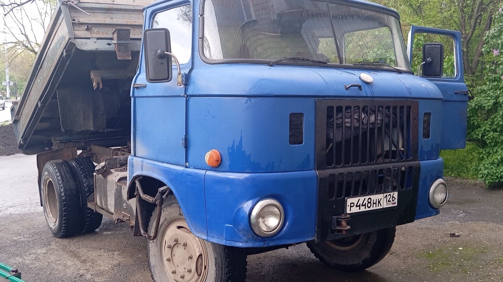 Front three-quarter view of a blue IFA W 50 L tipper truck with its bed raised.