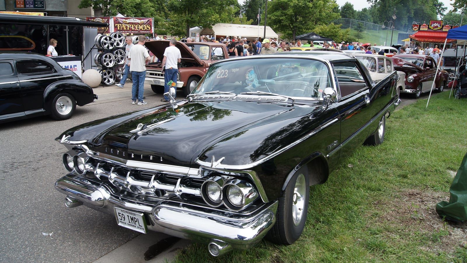 Black 1959 Imperial with quad headlights and tailfins, front three-quarter view.