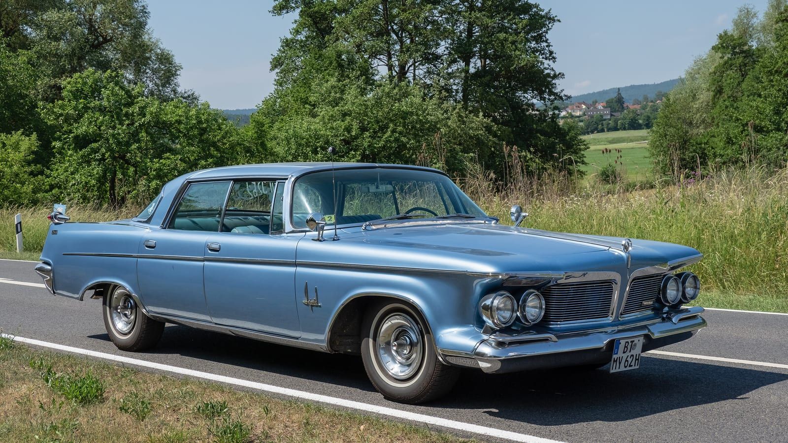 Light blue 1962 Imperial Crown hardtop on a country road, front three-quarter view.